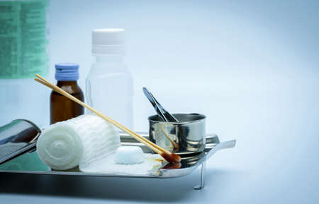 Wound care dressing set on stainless steel plate. Cotton ball with alcohol, cotton stick with povidone-iodine, forceps and conform bandage.の写真素材
