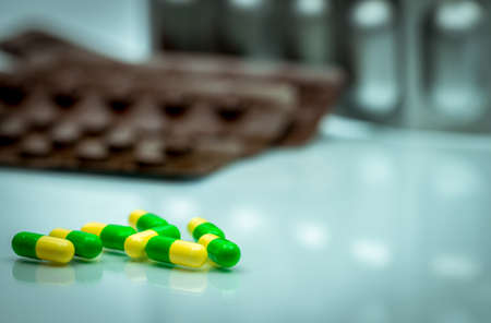 Green, yellow tramadol capsule pills on blurred blister pack background with copy space. Cancer pain management. Opioid analgesics. Drug abuse in teenage in Thailand.の写真素材