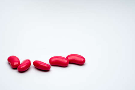 Five red kidney shape sugar coated tablet pills isolated on white background with copy spaceの写真素材