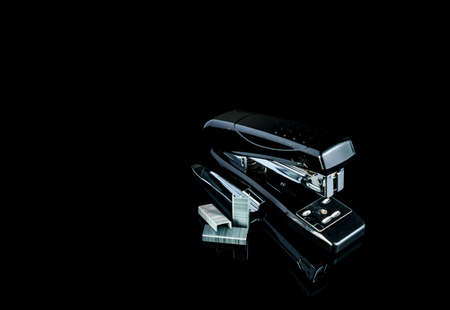 Black stapler and staples on dark background.の写真素材