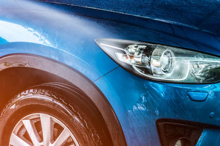 Blue compact SUV car with sport and modern design are washing with water. Car care service business concept. Car covered with drops of water after cleaning with high pressure water sprayの写真素材
