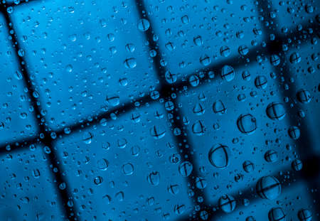Blue abstract blur background with water drops and reflection on transparent glass. Blue background for lonely, sad and missing someone on rainy day conceptの写真素材