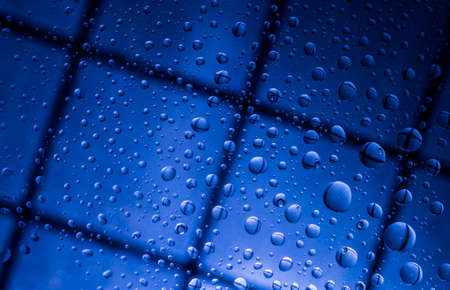 Blue abstract blur background with water drops and reflection on transparent glass. Blue background for lonely, sad and missing someone on rainy day conceptの写真素材