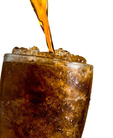 Soft drink pouring to glass with ice isolated on white background with clipping path and copy space. There is a drop of water on the transparent glass surface.の写真素材