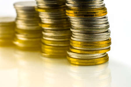 Macro shot detail of golden and silver color coin stacks on white background with flare light light and copy space for text. Business and finance growth, saving money, investment and interest concept.の写真素材