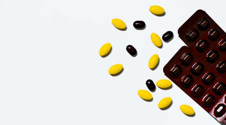 Macro shot of yellow oval tablet pills, black tablets pills on white background with creative pattern and black caplets pills in brown blister pack. Prepare pills before traveling abroad.の写真素材