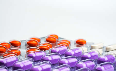 Macro shot detail of orange, purple and white tablets pills in blister pack on white background. Colorful medicine for relieve pain. NSAIDs drug for anti-inflammation can cause gastric ulcer.の写真素材