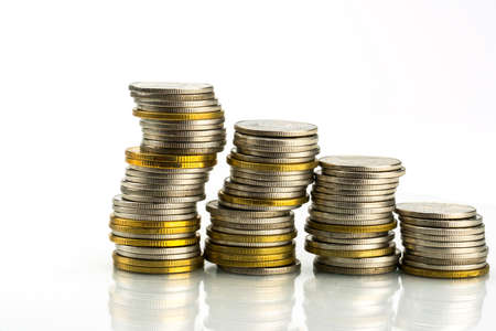 Macro shot detail of golden and silver color coin stacks on white background with copy space for text. Business and finance growth, saving money, investment and interest concept.の写真素材
