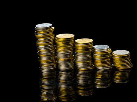 Macro shot detail of golden and silver color coin stacks on dark background with copy space for...