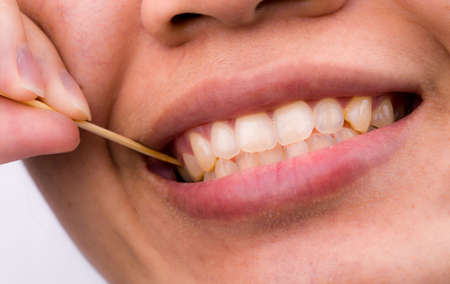 Asian woman clean her teeth from food stuck her teeth with bamboo wood toothpick after breakfast, lunch, dinner. Personal dental care with Asian style. Dental health and bad breath problem concept.の写真素材