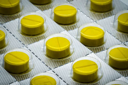 Macro shot detail of yellow tablets pill in blister pack. Full frame of tablet pillsの写真素材