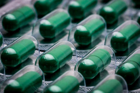 Andrographis paniculata extract for treatment common cold and sore throat. Standardized herbal medicine capsule pills in pack. Full frame of green capsule pills. Alternative medicine concept.の写真素材