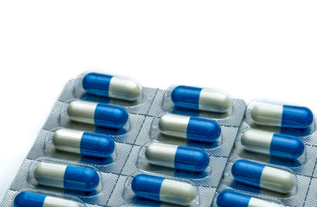 Blue-white capsule pills in blister pack isolated on white background with copy space for text....