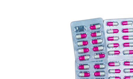 Quality control error in pharmaceutical manufacturing. Blister pack missing one capsule of antibiotic pill. Pink and white antimicrobial capsule pills isolated on white background with copy space.の写真素材