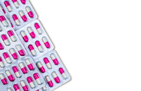 Pink, white antibiotic capsule pills in blister pack isolated on white background. Medicine for infections disease. Antibiotic drug used in food animals at animals farm spread of antibiotic resistanceの写真素材