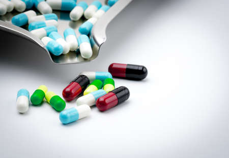 Colorful capsule pills on stainless steel drug tray on white background. Closeup many of capsule...