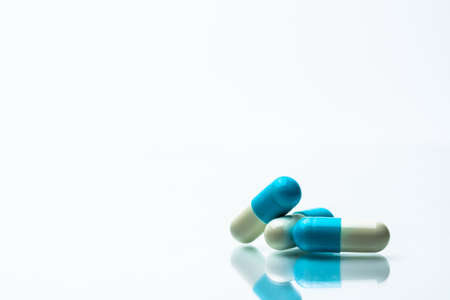 Three blue and white capsules pills on white background with shadows and copy space for text.の写真素材