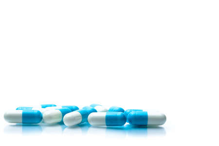 Pile of blue and white capsules pills isolated on white background with shadows and copy space for text. Global healthcare concept.の写真素材