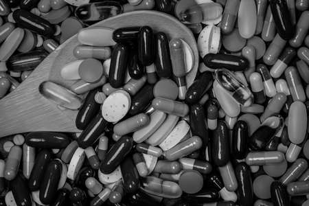 Many of tablets and capsules pills and wood spoon in black and white picture. Drug overuse and overdose concept. Drug use in elderly people with chronic disease lead to kidney disease.の写真素材