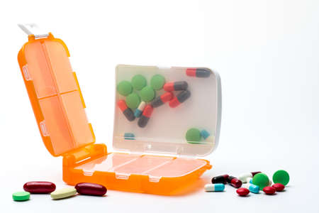 Orange pills box with tablets and capsule pills isolated on white background with copy space....
