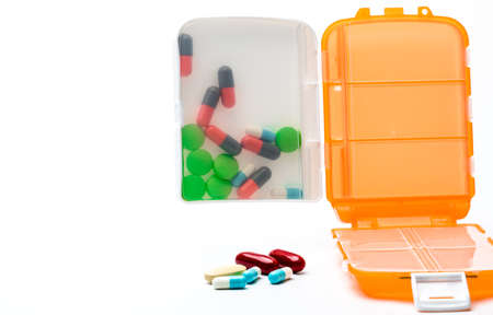 Orange pills box with colorful capsule pills isolated on white background with copy space. Prepare medicine before work or travel abroad concept.の写真素材