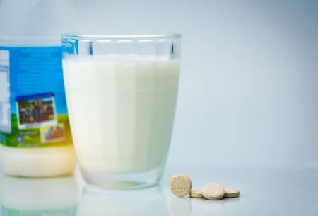 Sweetened flavored milk tablets and one glass of milk and milk bottle on white background. Calcium food products from cow milk for healthy bone.の写真素材