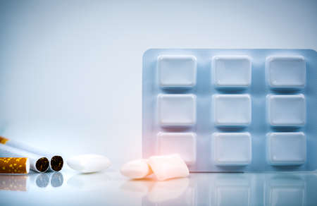 Nicotine chewing gum in blister pack near pile of cigarette. Quit smoking by use nicotine gum for relief of nicotine withdrawal symptoms. Medicine for giving up smoking. World no tobacco day concept.の写真素材