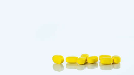 Yellow tablets pills isolated on white background with copy space for text. Ibuprofen tablets pills. Painkiller medicine for headache, high fever and anti inflame. Pharmaceutical industry concept.の写真素材