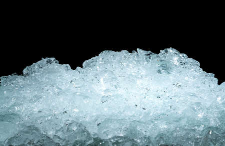 Pile of crushed ice cubes on dark background with copy space. Crushed ice cubes foreground for beverages, beer, whisky, fruit juice, milk, fresh food or fresh vegetables.の写真素材