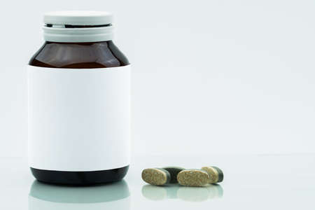 Vitamins, supplements and minerals dual layer tablets pills and medicine amber glass bottle with blank label isolated on white background with copy space. Use for vitamins and supplements advertising.の写真素材