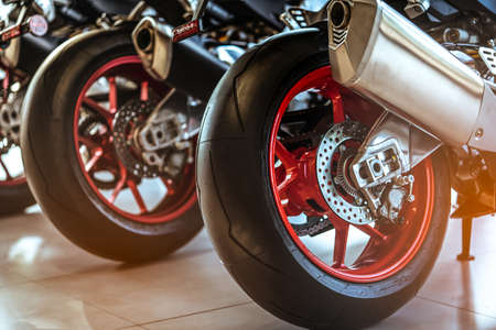 Closeup of new motorbike rear wheel . Big bike parked in showroom of dealership.  Motorcycle exhaust...
