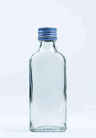 Empty transparent glass bottle with closed aluminum cap isolated on white background with blank label and copy space. Use for beverage or medicine product design template. Glass bottle packaging.の写真素材