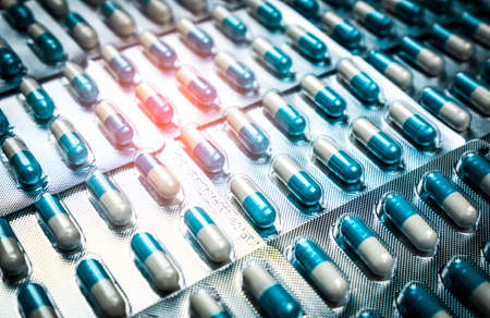Blue and white capsules pill in blister pack arranged with beautiful pattern. Global healthcare concept. Antibiotics drug resistance. Antimicrobial capsule pills. Pharmaceutical industry.の写真素材