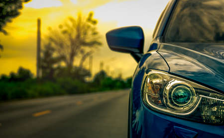 Front view of luxury blue compact SUV car with sport and modern design parked on asphalt road at sunset. Hybrid auto and automotive concept. Road trip and car driving for travel.の写真素材