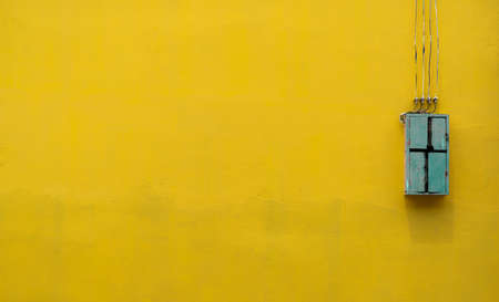 Green wooden box, electric control equipment in the factory on yellow vintage concrete wall background with copy space. Safety in home and factory industrial concept. Vintage style backgroundの写真素材