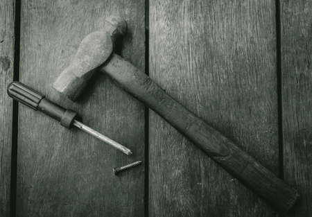 Top view of old hammer, screwdriver and nail on old wooden table. Woodwork tools for fix and repair home. Carpentry tools on an old workbench. DIY tool kit. Equipment for construction in house.の写真素材