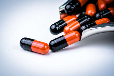 Selective focus of orange and black capsule pills on stainless steel drug tray. Antibiotics resistance. Global healthcare. Antibiotics drug resistance. Antimicrobial capsule pills. Pharmacy backgroundの写真素材