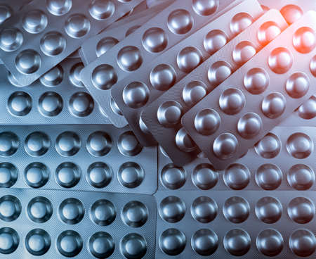 Closeup pile of tablets pills in silver blister pack. Pharmaceutical industry concept. Global healthcare. Health budgets. Pharmaceutical packaging concept. Pharmacy drugstore. Drug overuse concept.の写真素材