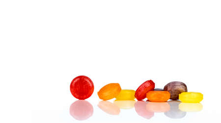 Medical lozenges for relief cough, sore throat and throat irritation isolated on white background. Cough and colds drop. Colorful cough pastille. Red, orange, yellow, and purple round candy or sweets.の写真素材