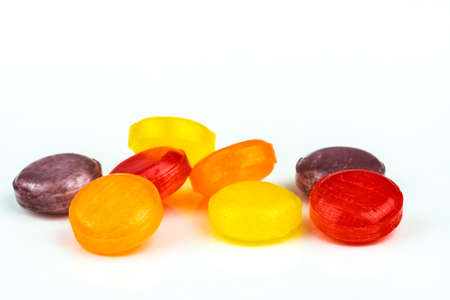 Medical lozenges for relief cough, sore throat and throat irritation isolated on white background. Cough and colds drop. Colorful cough pastille. Red, orange, yellow, and purple round candy or sweets.の写真素材
