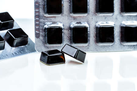 Medical pastille for relief cough, sore throat and throat irritation isolated on white background. Cough and colds drop. Black cough herbal extract lozenges in blister pack. Square candy or sweets.の写真素材