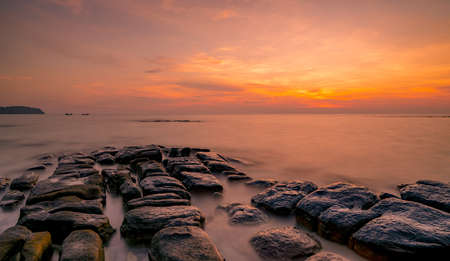 Rocks on stone beach at sunset. Beautiful beach sunset sky. Twilight sea and sky. Tropical sea at dusk. Dramatic sky and clouds. Sunset abstract background. Calm and relax life. Nature landscape.の写真素材