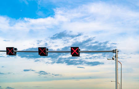 Traffic signal light with red color of cross sign on blue sky and white clouds background. Wrong sign. No entry traffic sign. Red cross guidance stop go traffic signal light. Warning traffic light.の写真素材