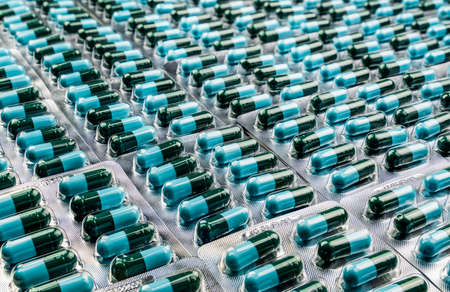 Closeup green-blue antibiotic capsule pills in blister pack. Antimicrobial drug resistance. Pharmaceutical industry. Global healthcare. Pharmacy background. Pharmaceutical product. Amoxicillin capsuleの写真素材