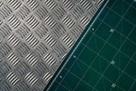 Industrial metal checker plate and green cutting mat. Metal checker plate texture background. Metal checkerplate for anti skid. Embossed metal sheet floor. Silver bump ground with art pattern.の写真素材