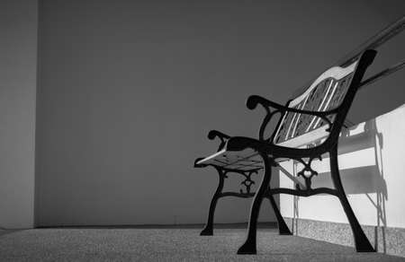 Empty wrought iron bench placed near stairs of the building. Sunshine in to the concrete building....