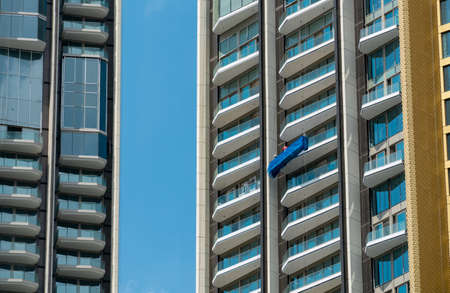 High rise window cleaner with cradle lift. Glass cleaner is working. Dangerous jobs in the building,...