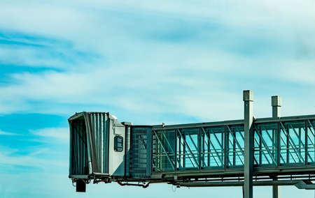 Jet bridge after commercial airline take off at the airport against blue sky and white clouds....