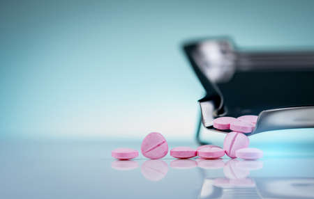 Pink tablet pills on stainless steel drug tray. Pharmaceutical industry. Neurotropic vitamins. Medication use in hospital or drugstore. Drug retail market. Medicine for peripheral neuropathies.の写真素材