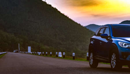 Blue SUV car parked on asphalt road in front of the mountain. Car parked at the park in early...